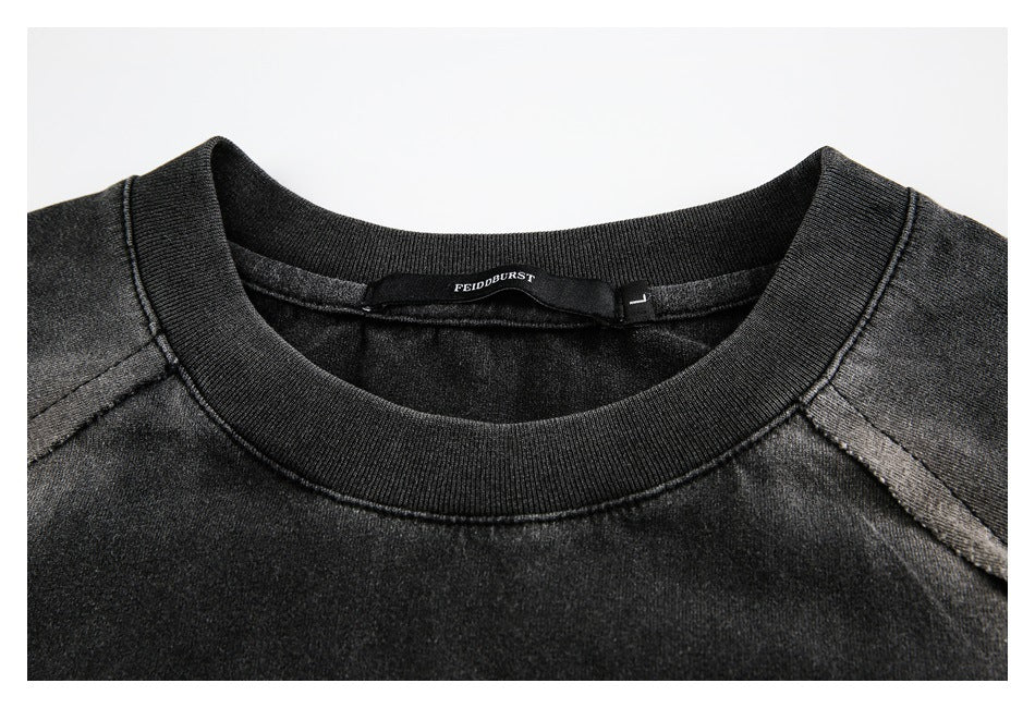 Close-up of a black shirt's ribbed crew neck, shoulder seams, and inner brand and size labels.