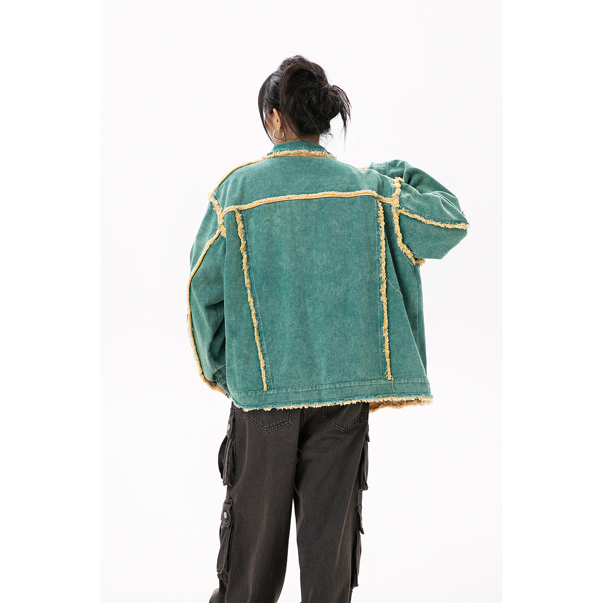 Back view of a model wearing an oversized teal jacket with yellow frayed seam trim.