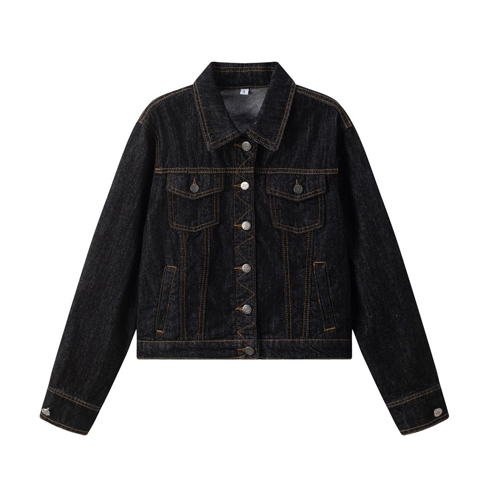 Black denim trucker jacket flat lay, front view, with chest flap pockets, silver buttons and golden-brown topstitching
