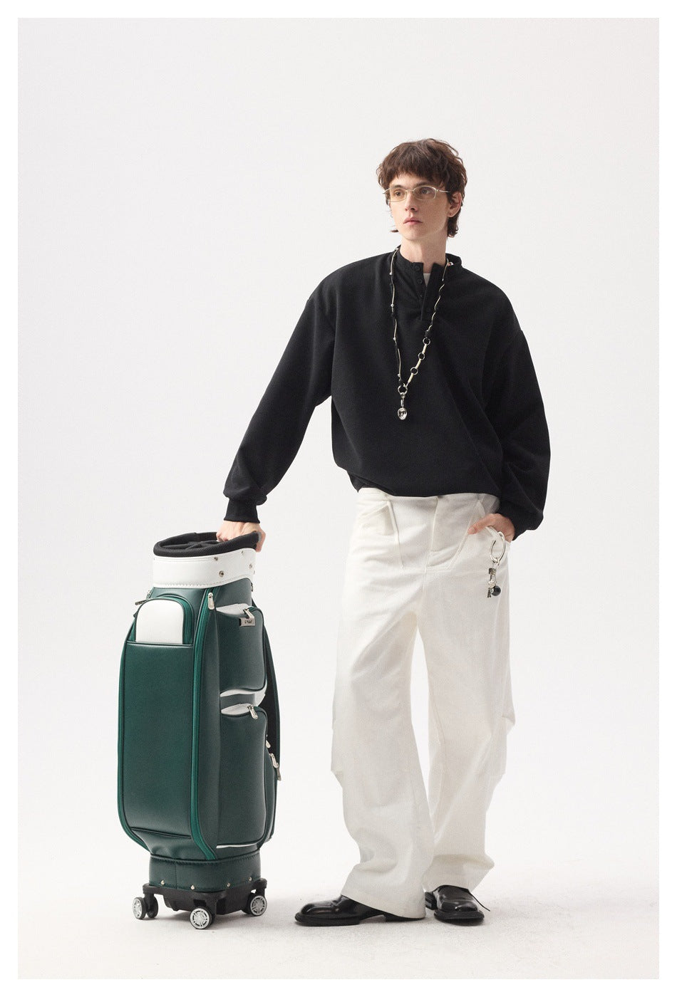 Full-length model wearing an oversized black button-neck top, white wide-leg trousers, and black shoes.