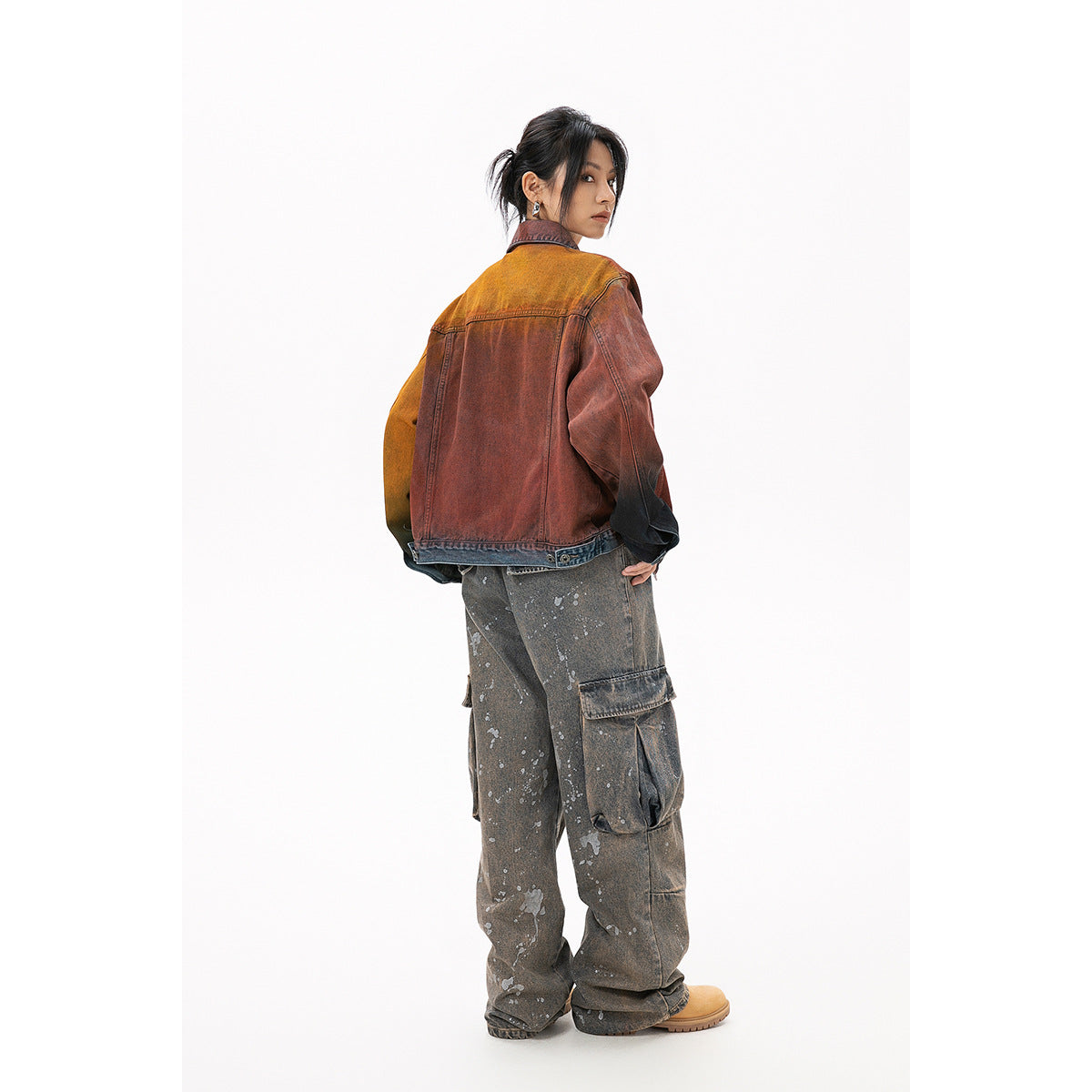 Rear view of a model wearing a rust-red washed denim jacket with ochre and dark contrasting sleeves.