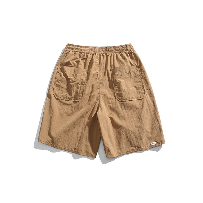 Back view of tan shorts with an elastic waistband and two large rear patch pockets, on a white background.