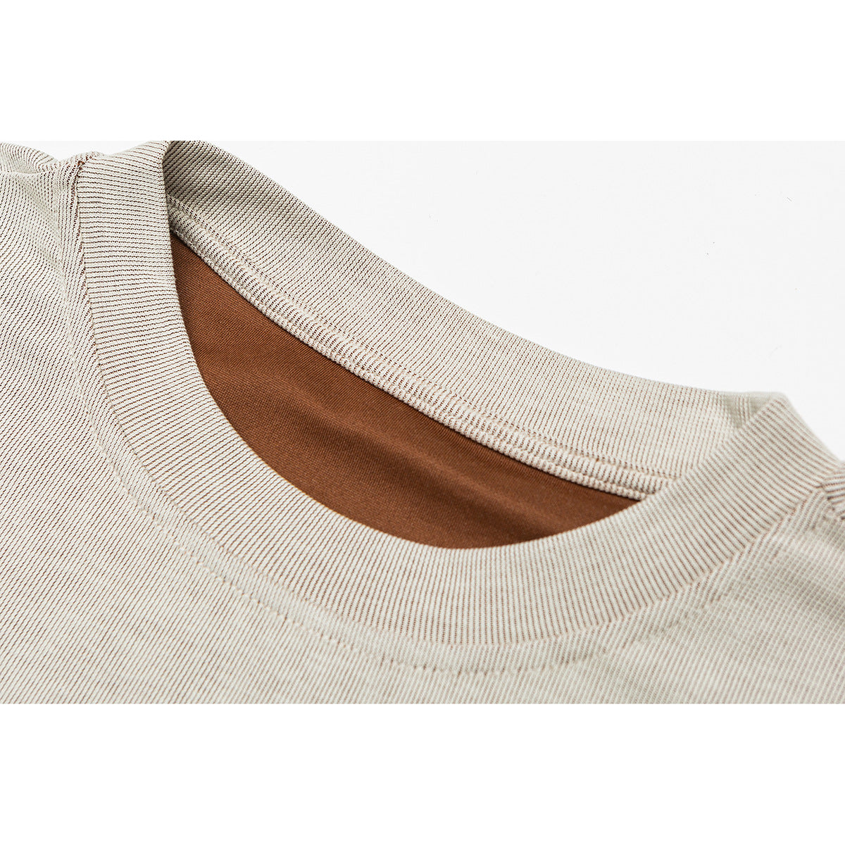 Close-up of a cream ribbed crew neckline with brown inner neck binding.