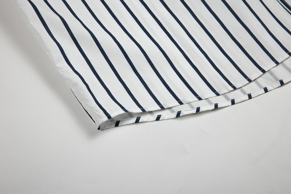 Close-up of the curved hem and double stitching on a white shirt with navy vertical stripes.
