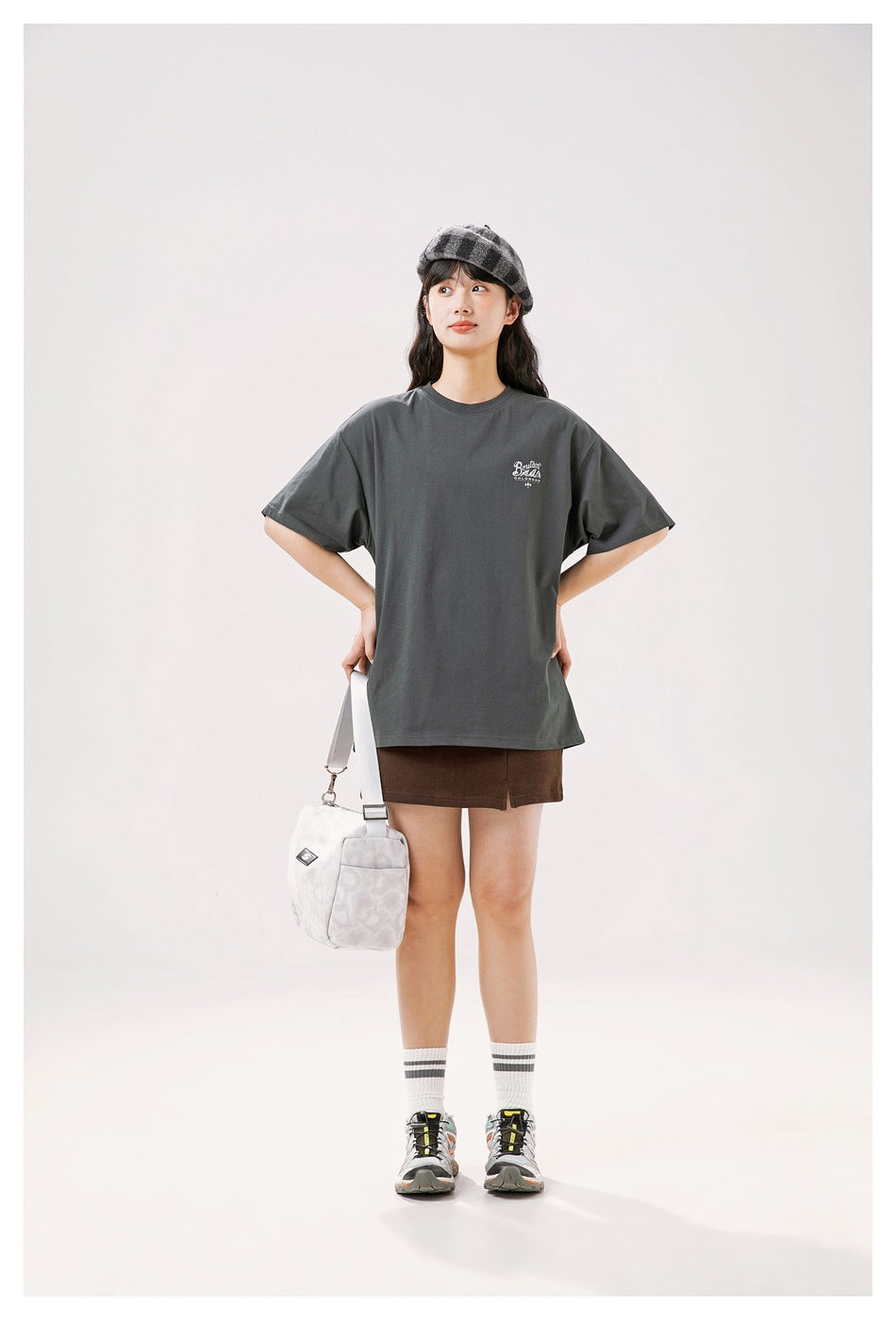 Model wearing a charcoal oversized T-shirt with a small white chest print, shown from the front.