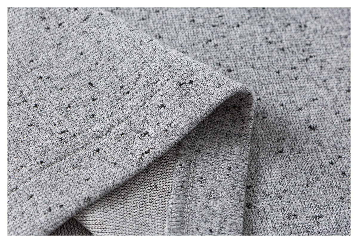 Close-up of the gray flecked knit sweater’s folded fabric and interior seam stitching.