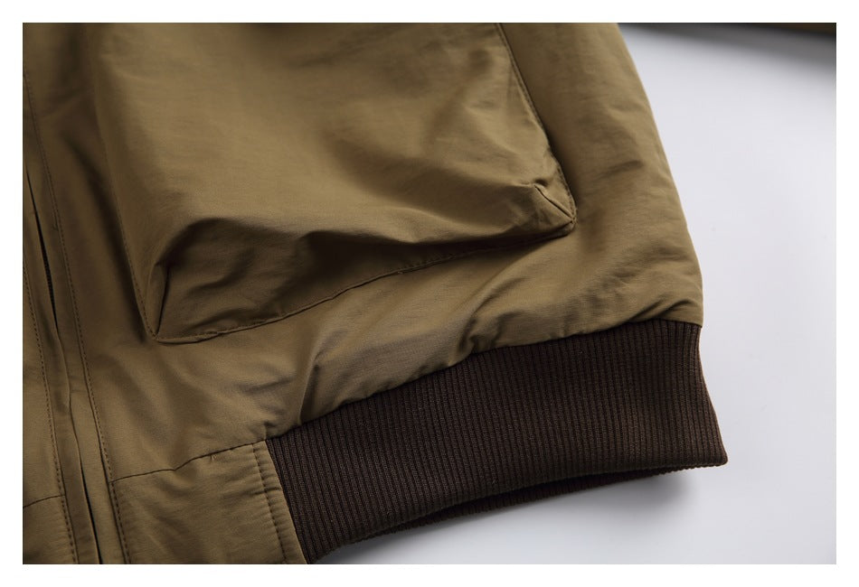 Close-up of an olive-brown jacket pocket above a dark brown ribbed waistband.