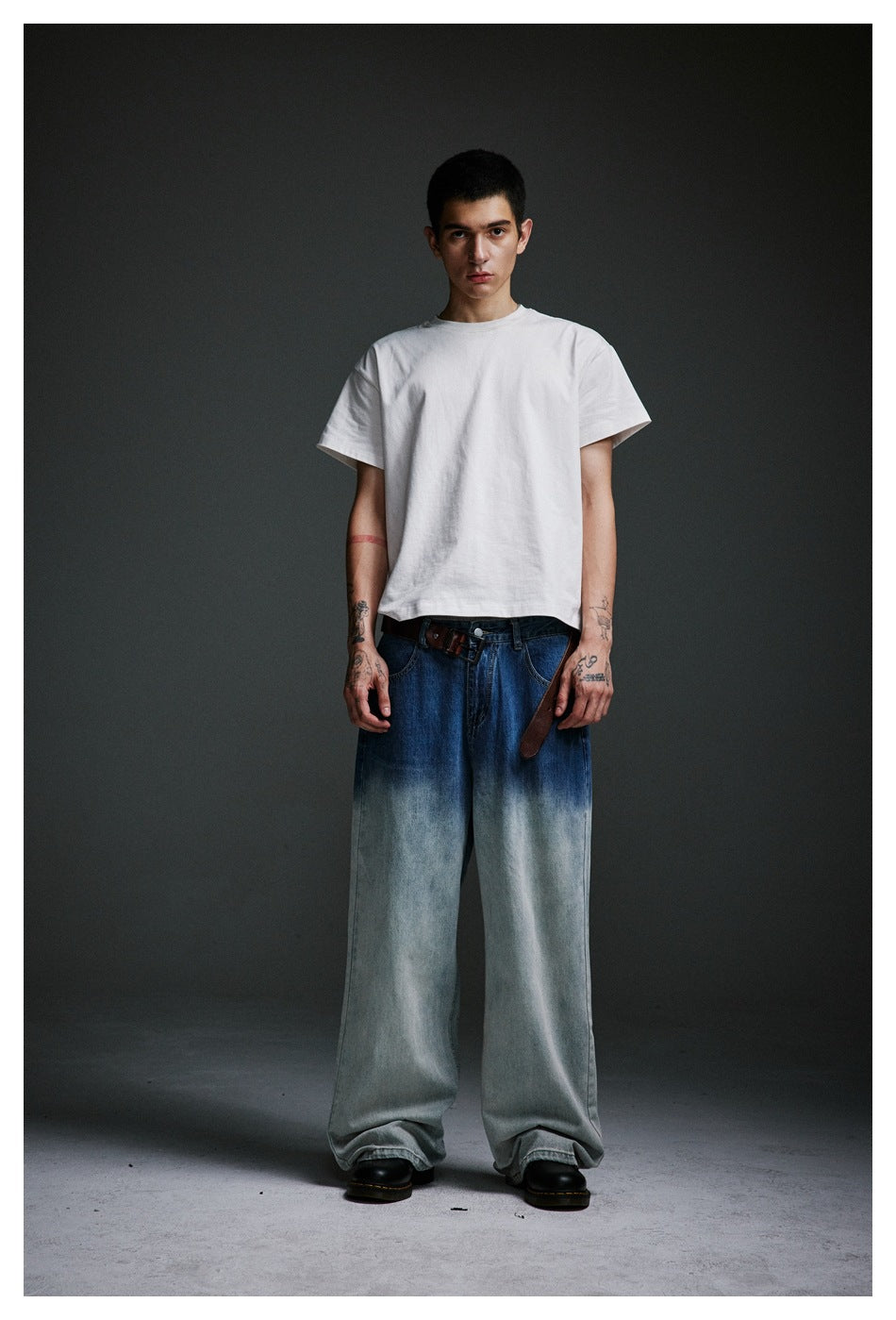 Front view of a model wearing a white T-shirt and very wide jeans with a blue-to-pale-wash finish.