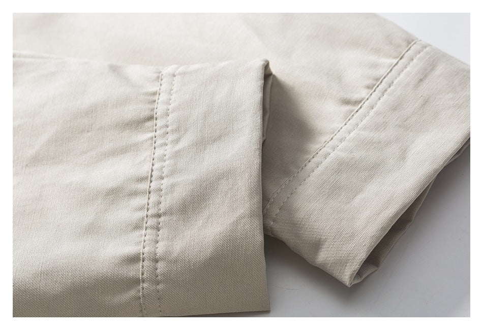 Close-up of a light beige garment sleeve and stitched cuff laid flat.