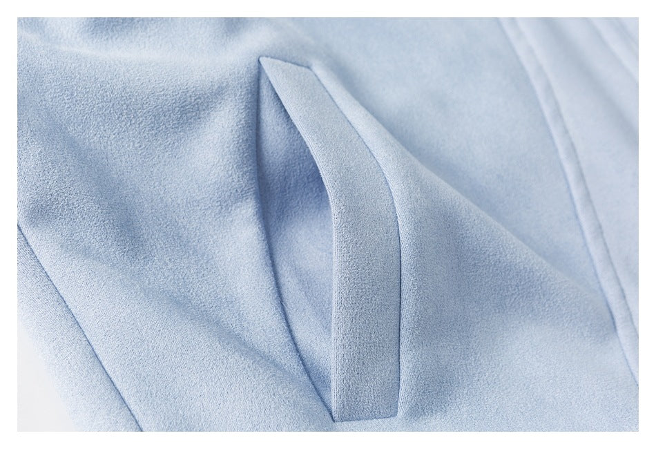 Close-up of a pale blue garment's angled pocket opening and stitched edges.
