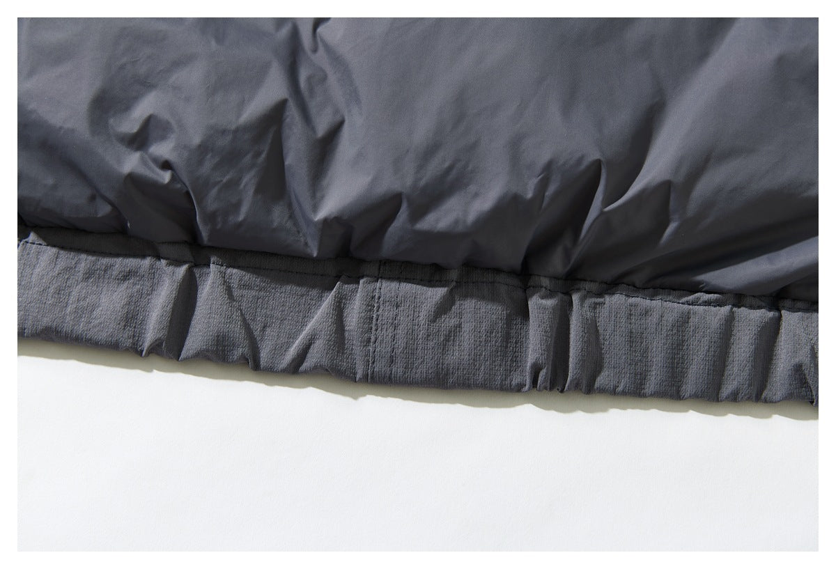 Close-up of a dark charcoal garment with a gathered, stitched hem against a white background.