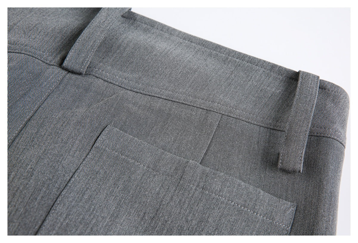 Close-up of charcoal-gray trouser waistband, belt loops, and pocket stitching.