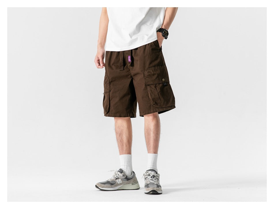 Model wearing coffee brown cargo shorts with white tee and gray sneakers, cropped front view