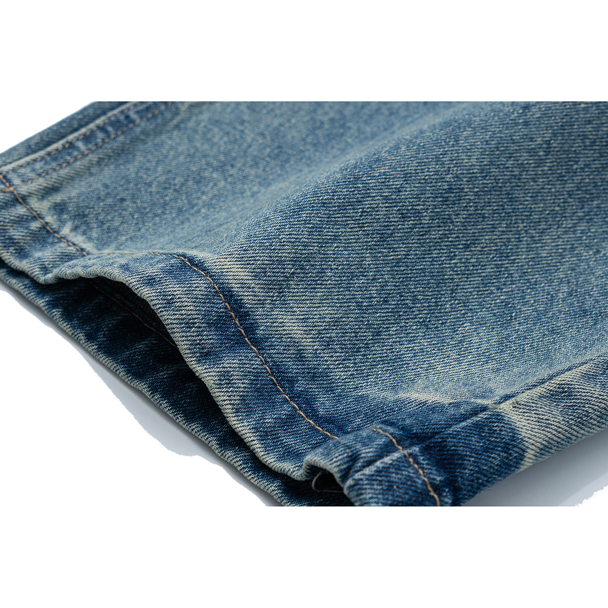 Close-up of a turned-up hem on blue jeans, showing denim texture and stitching.