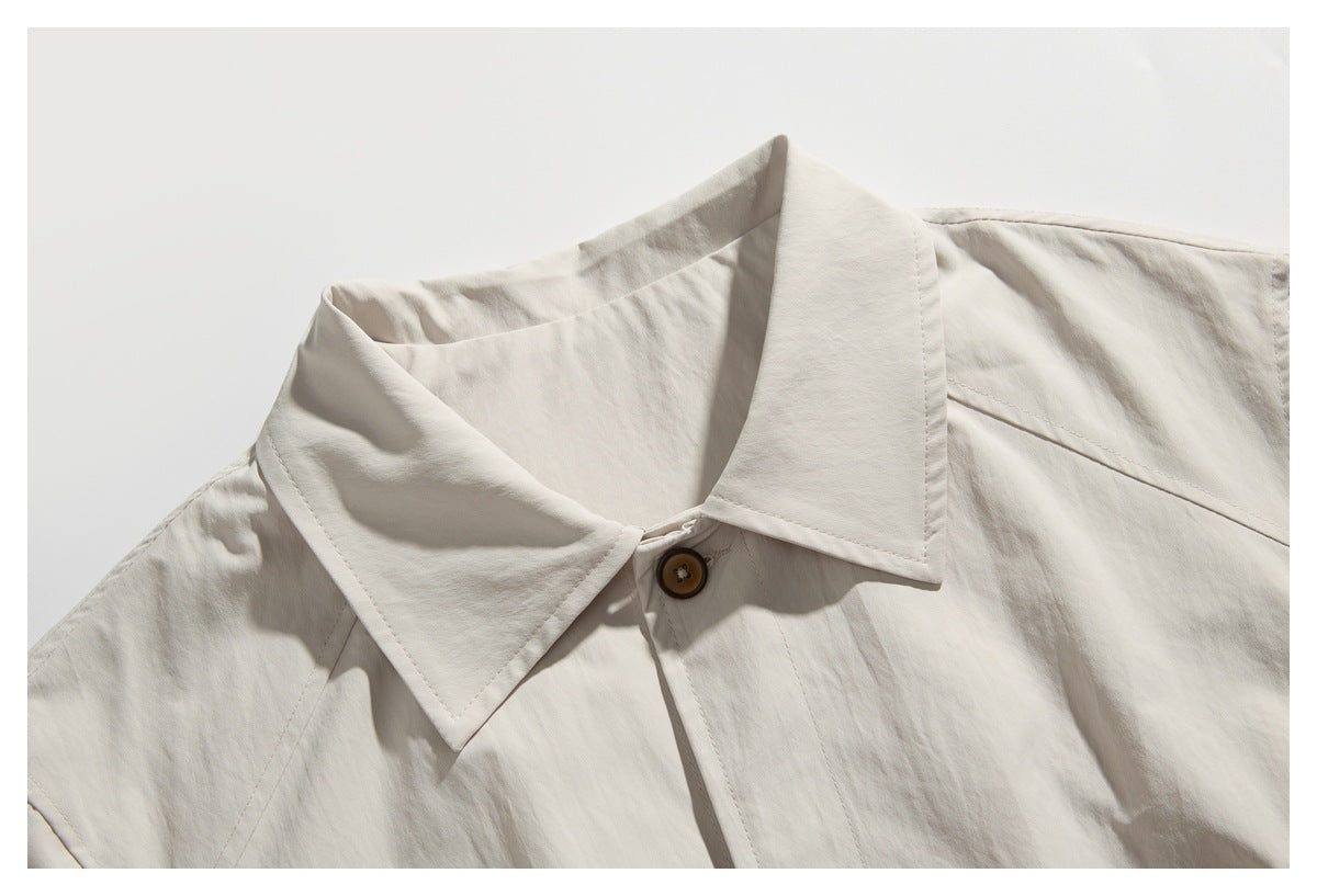 Close-up of an off-white collared garment showing the pointed collar, stitching, and a brown button.