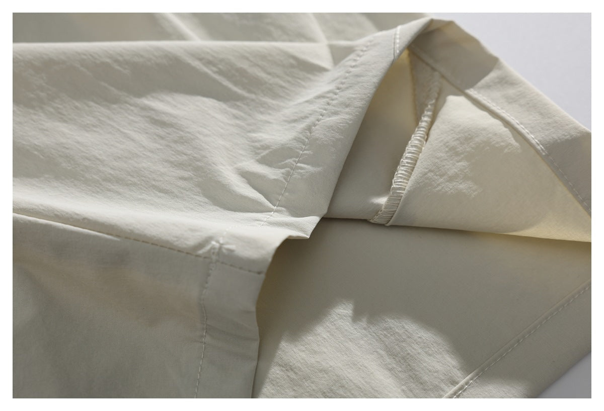 Close-up of off-white garment seams and folded fabric, showing stitching and a gathered edge.
