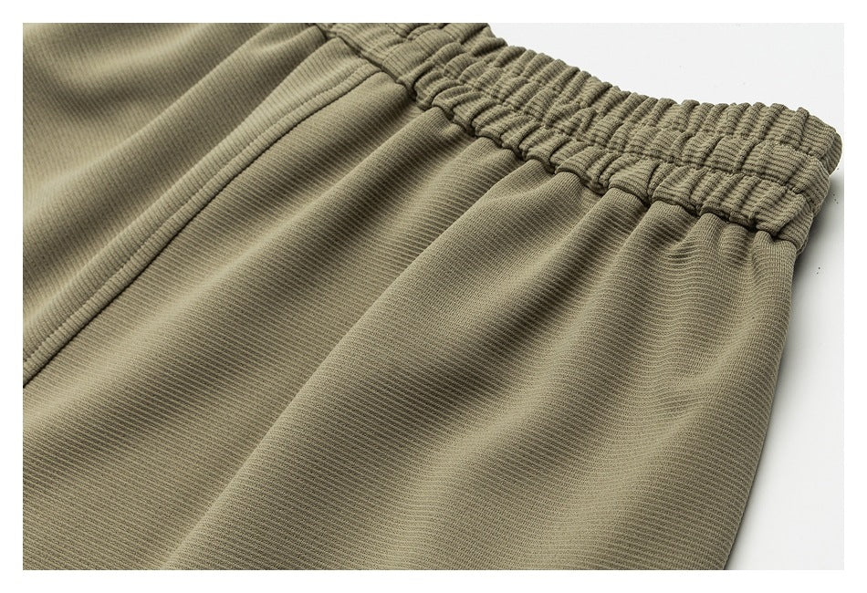 Close-up of olive-khaki pants showing the gathered elastic waistband and fine ribbed fabric.