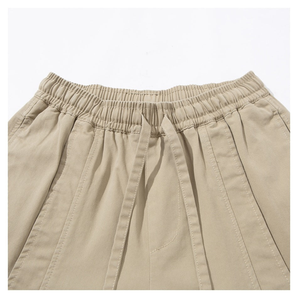 Close-up of beige wide-leg pants showing the gathered elastic waistband, matching drawstring and stitched panels.