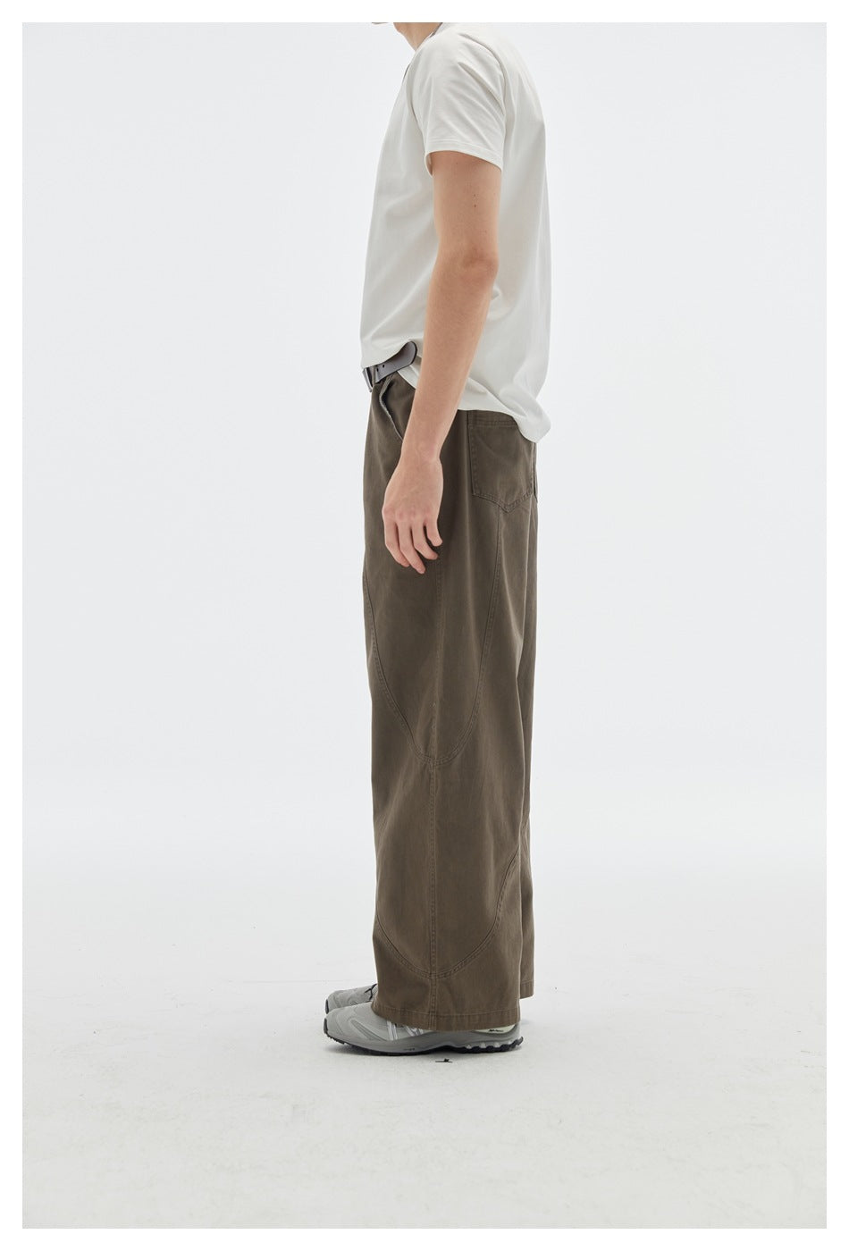 Side view of a model wearing dark brown wide-leg pants with curved panel seams and a white T-shirt.