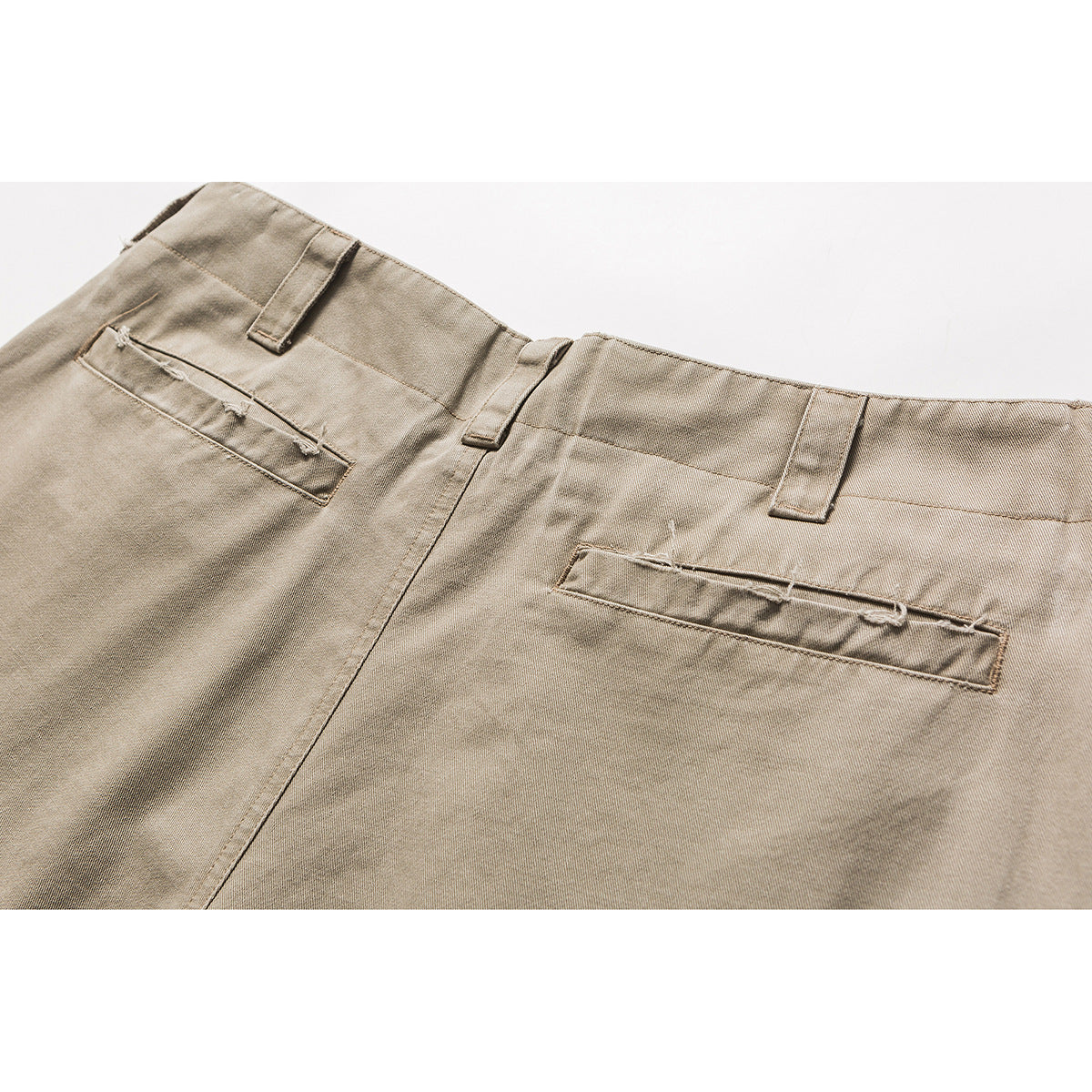 Close-up of the back waist and welt pockets of beige trousers.