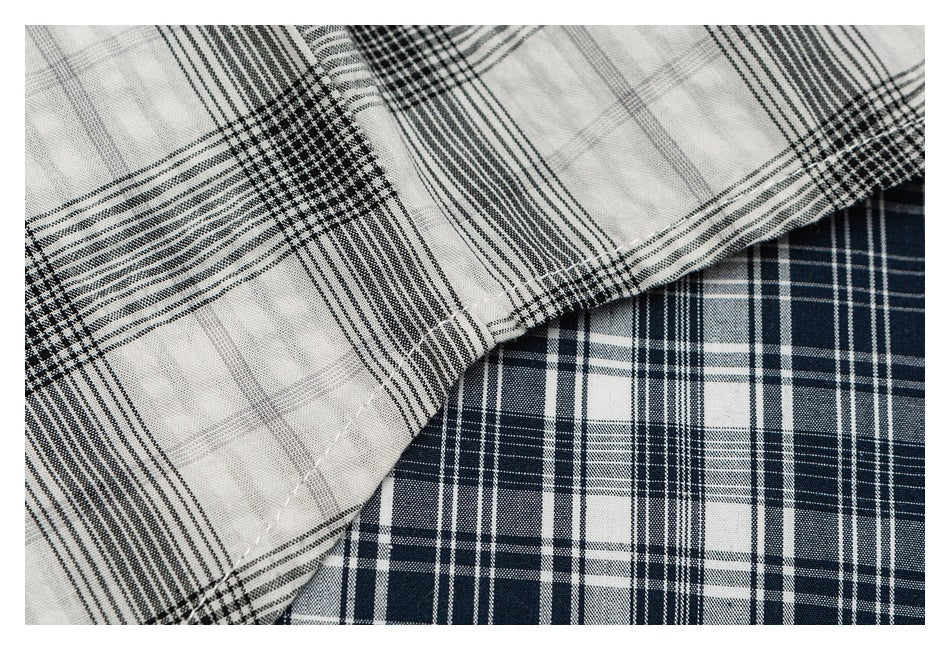 Close-up of folded fabric with contrasting navy-and-white and gray-and-black plaid patterns.