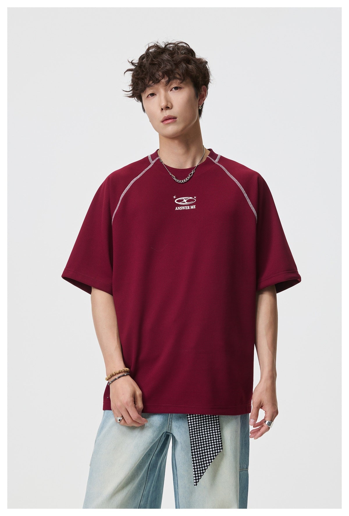 Front view of a model wearing a burgundy short-sleeve shirt with contrast seams and a small white chest graphic.