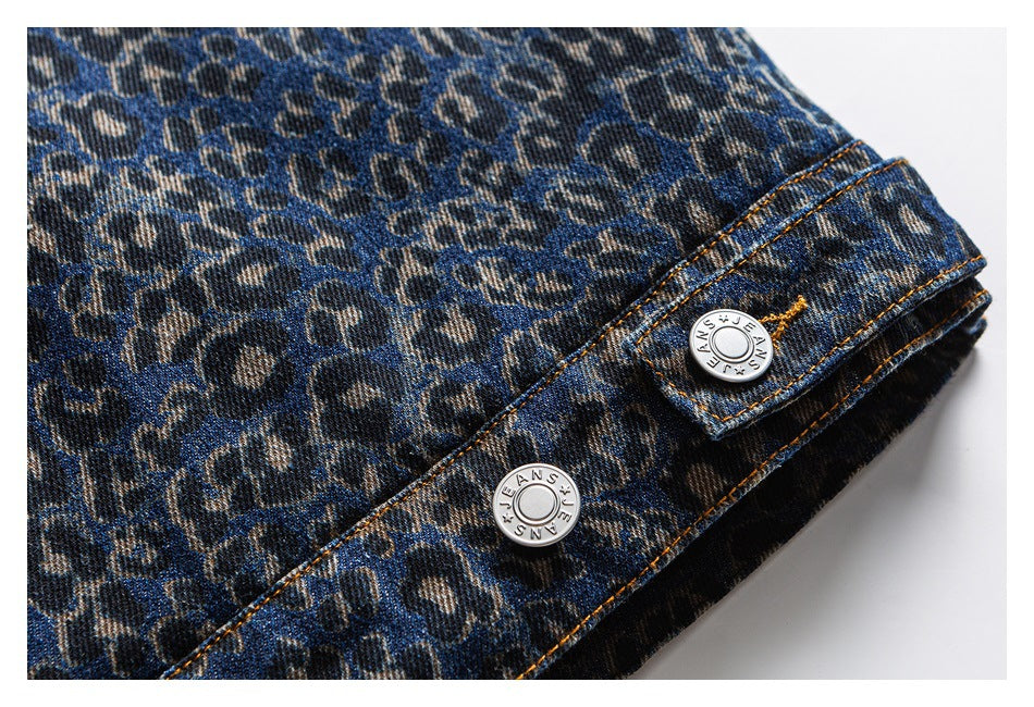 Close-up of leopard-print blue denim, orange stitching, and two silver buttons marked “JEANS.”