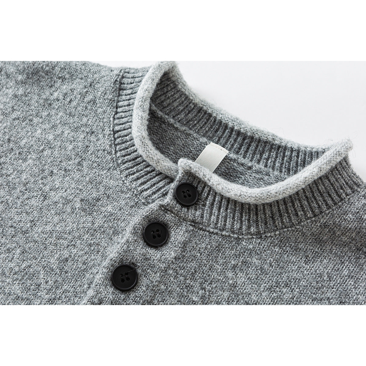 Close-up of a gray knit sweater's ribbed crew neck and three-button placket.