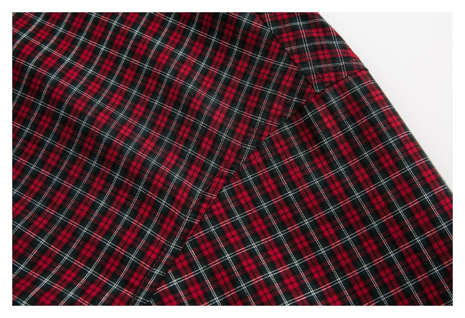 Close-up of a seam and overlapping panels on a red, black, and white plaid garment.