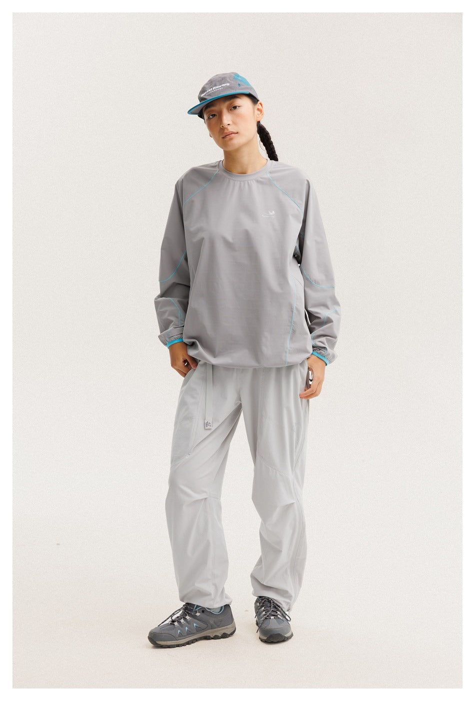 Front view of a model in a gray long-sleeve top with turquoise piping and matching light-gray pants.