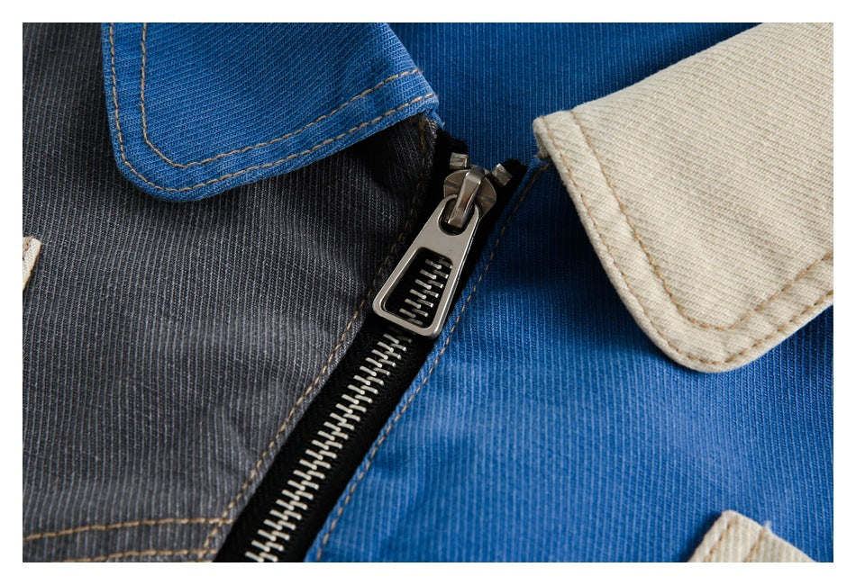 Close-up of the jacket's metal zipper and contrasting blue, charcoal, and cream panels.