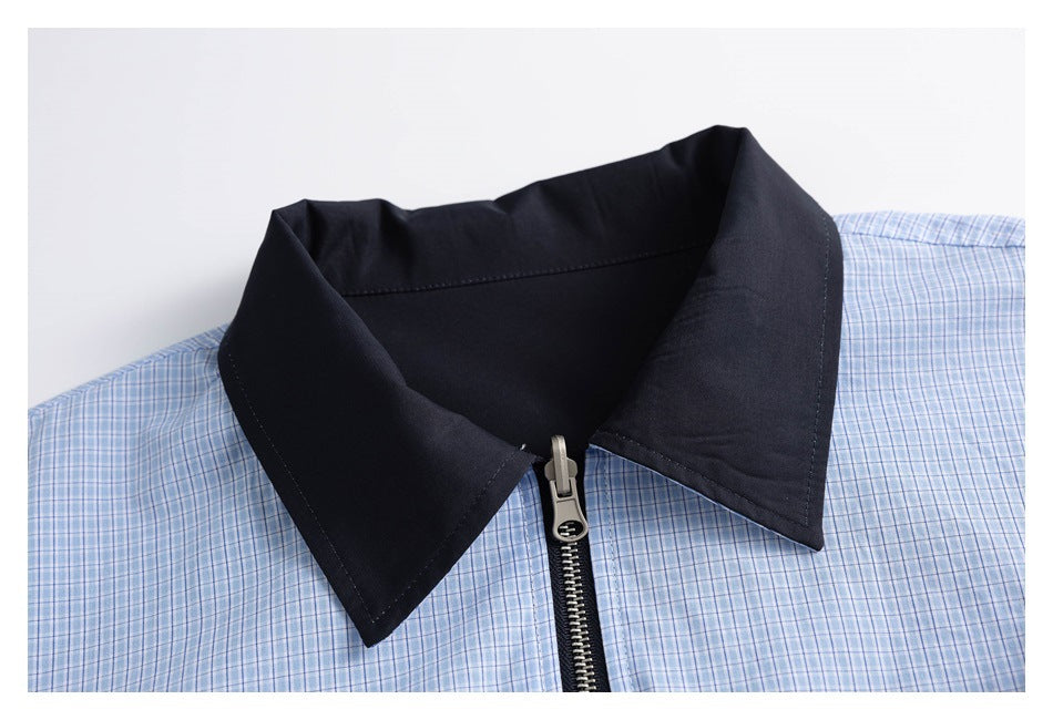 Close-up of a light blue plaid garment with a wide black collar and front zipper.
