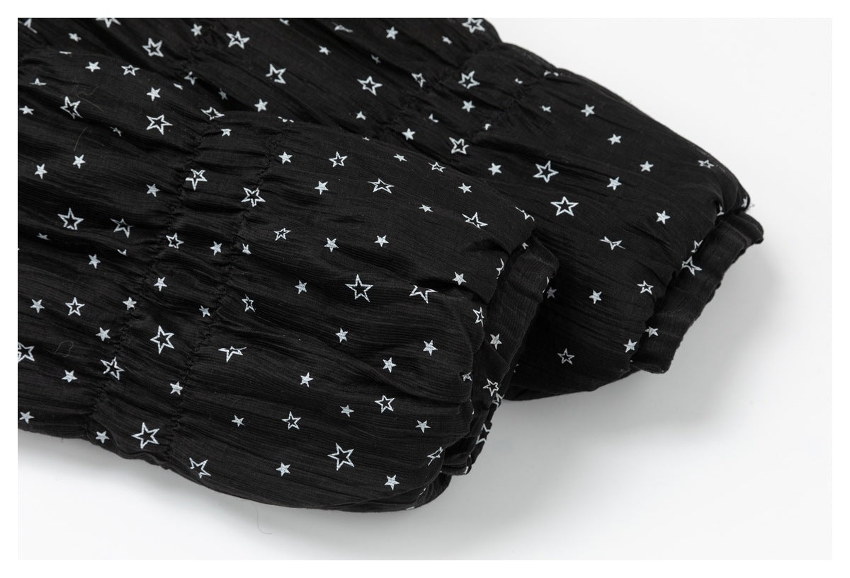 Close-up of gathered seams and folded edges on black fabric printed with white stars.