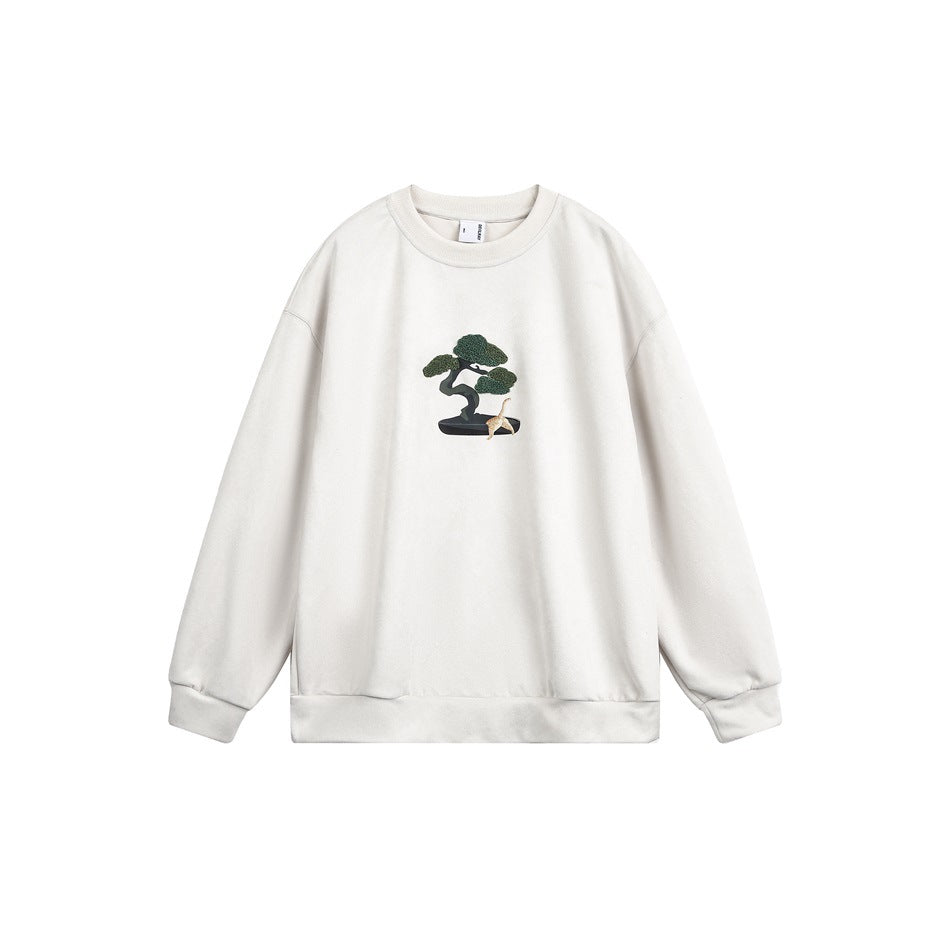 Beige crew-neck sweatshirt flat lay with embroidered bonsai pine tree and small cat on the chest