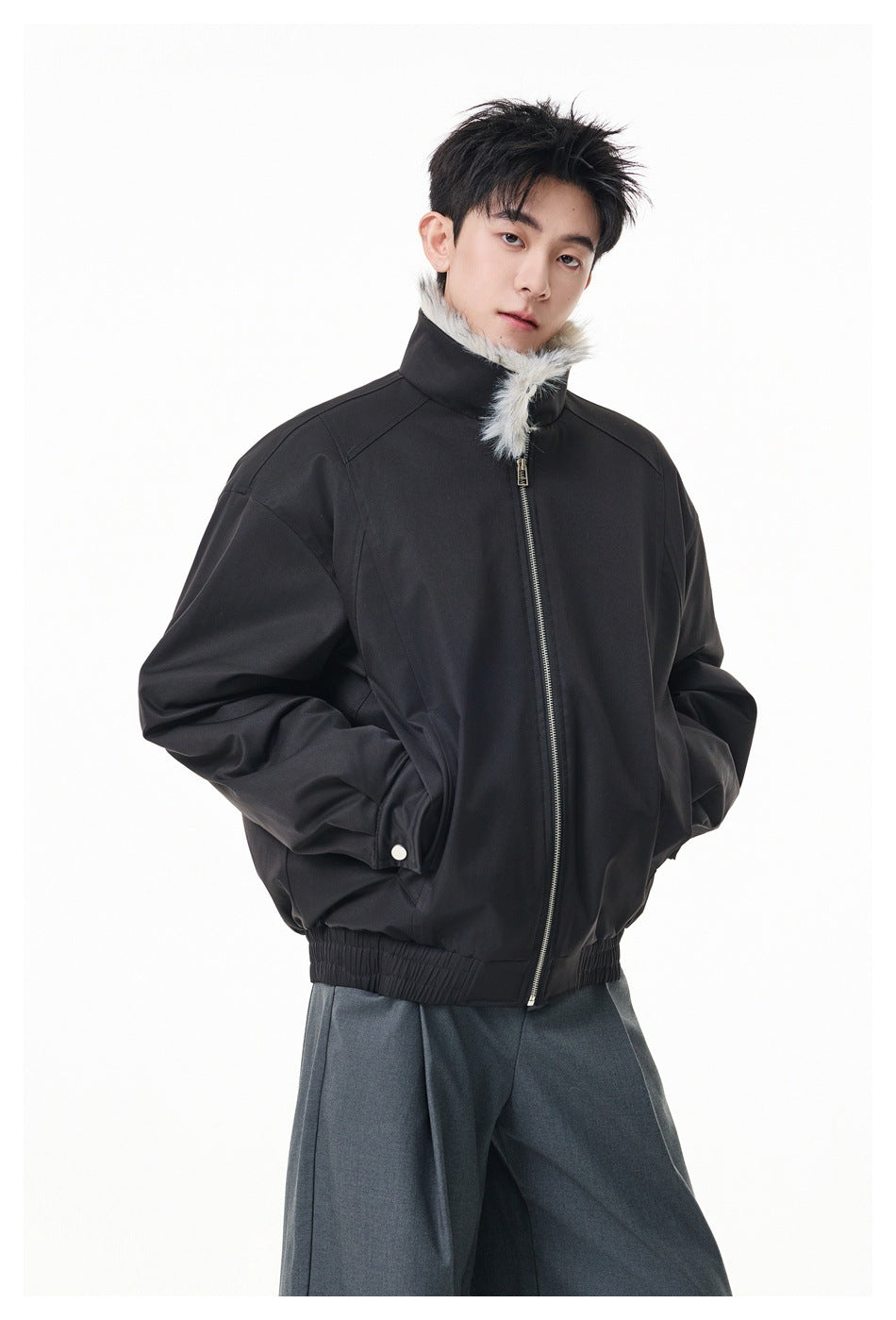 Model wearing a black jacket zipped to a high collar with light gray fur trim.