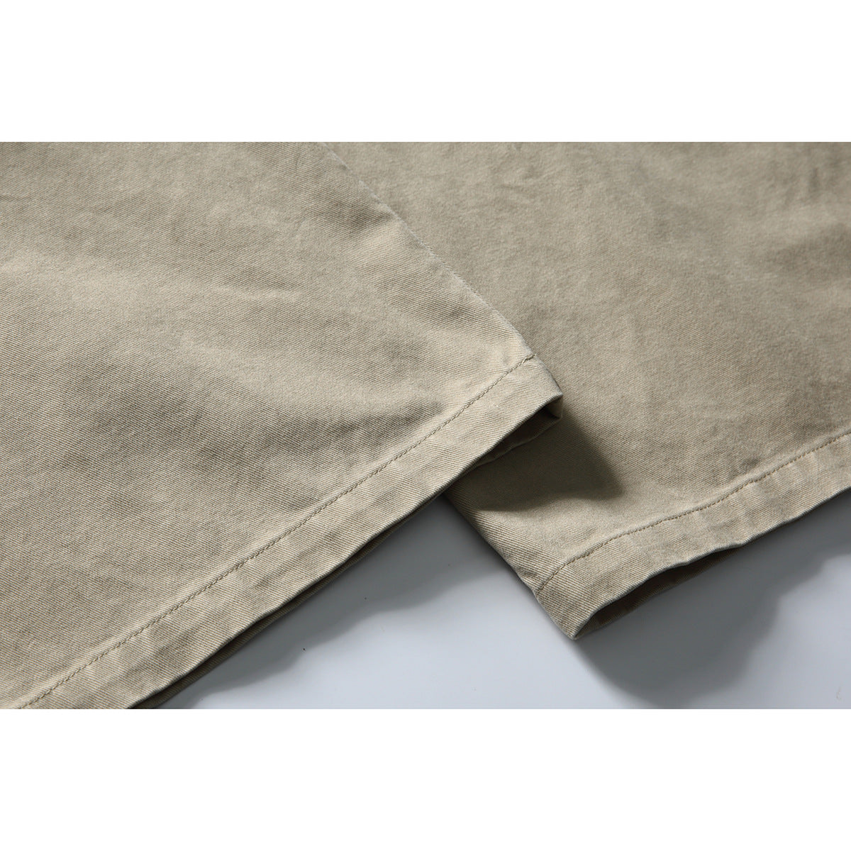 Close-up of the stitched hems on beige trouser legs.