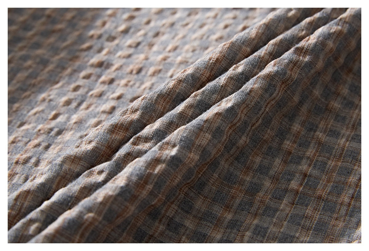 Close-up showing the textured gray-brown patterned shirt fabric gathered into soft folds.