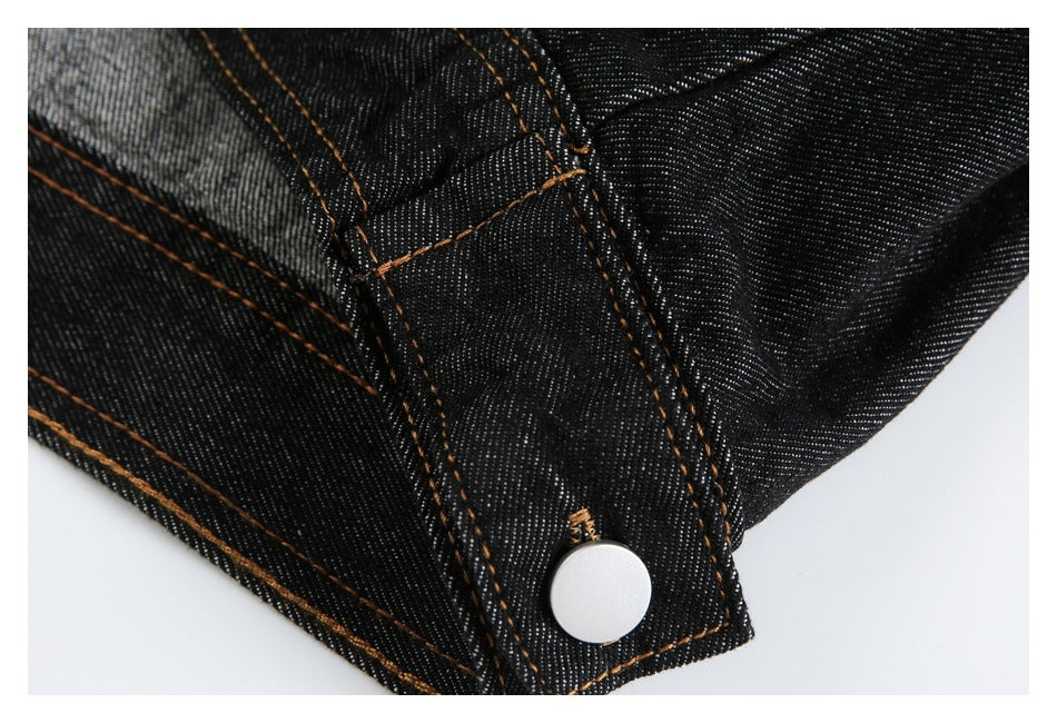 Close-up of a black denim placket edge with orange stitching and a silver snap button.