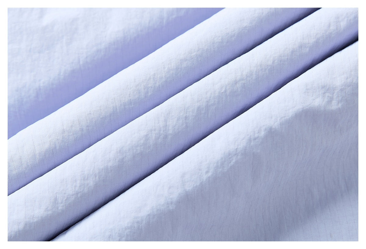Close-up of pale blue fabric arranged in diagonal folds, showing a fine woven texture.