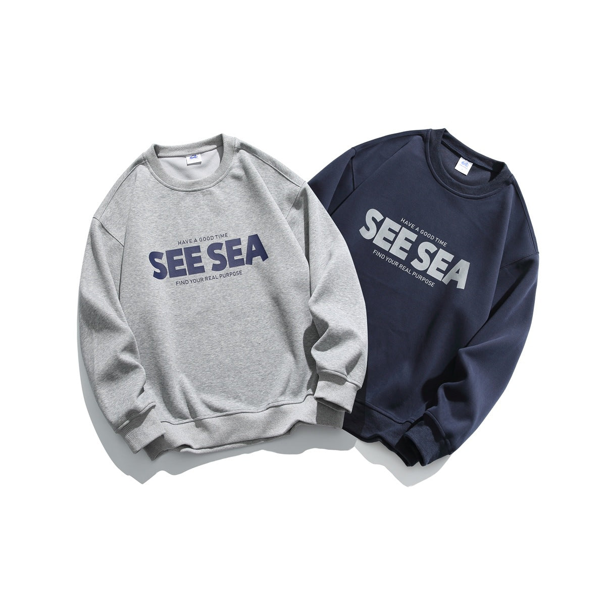 Two crewneck sweatshirts shown from the front: heather gray and navy, both with contrasting “SEE SEA” chest prints.