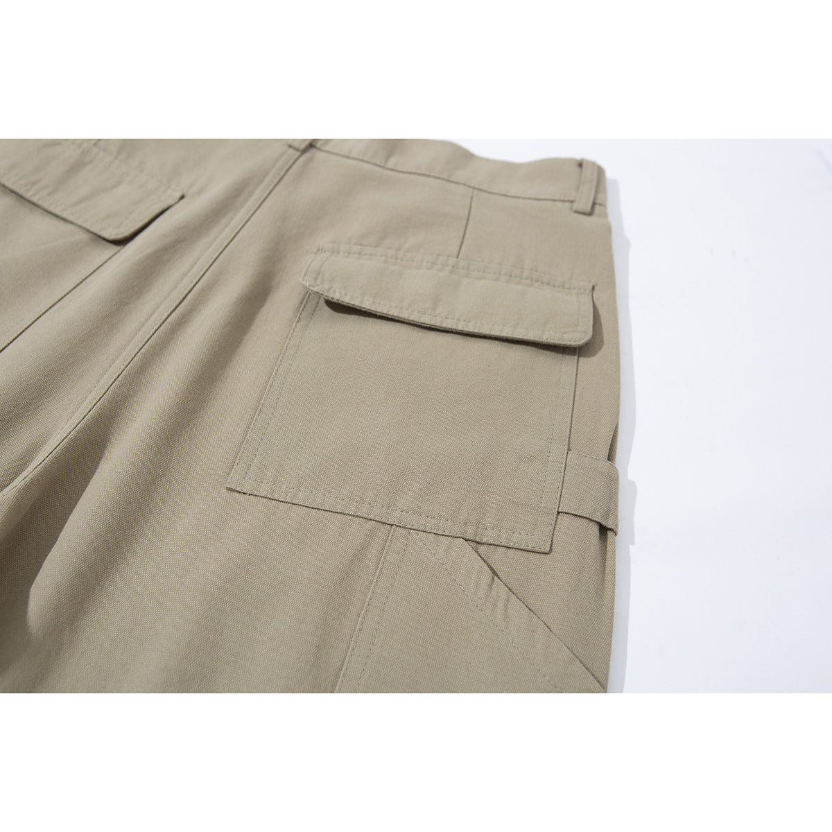 Close-up of a beige trouser leg with a large flap cargo pocket and stitched panel details.
