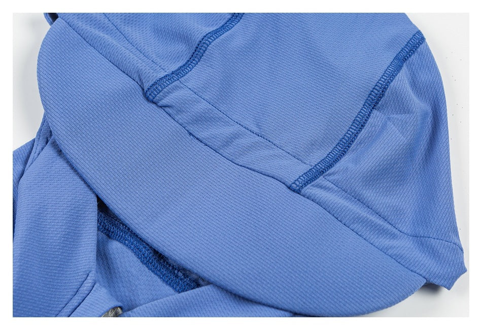 Blue garment close-up showing curved panels and dark overlock stitching.