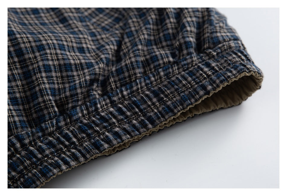 Close-up of a gathered elastic edge on dark blue, beige, and black plaid fabric.