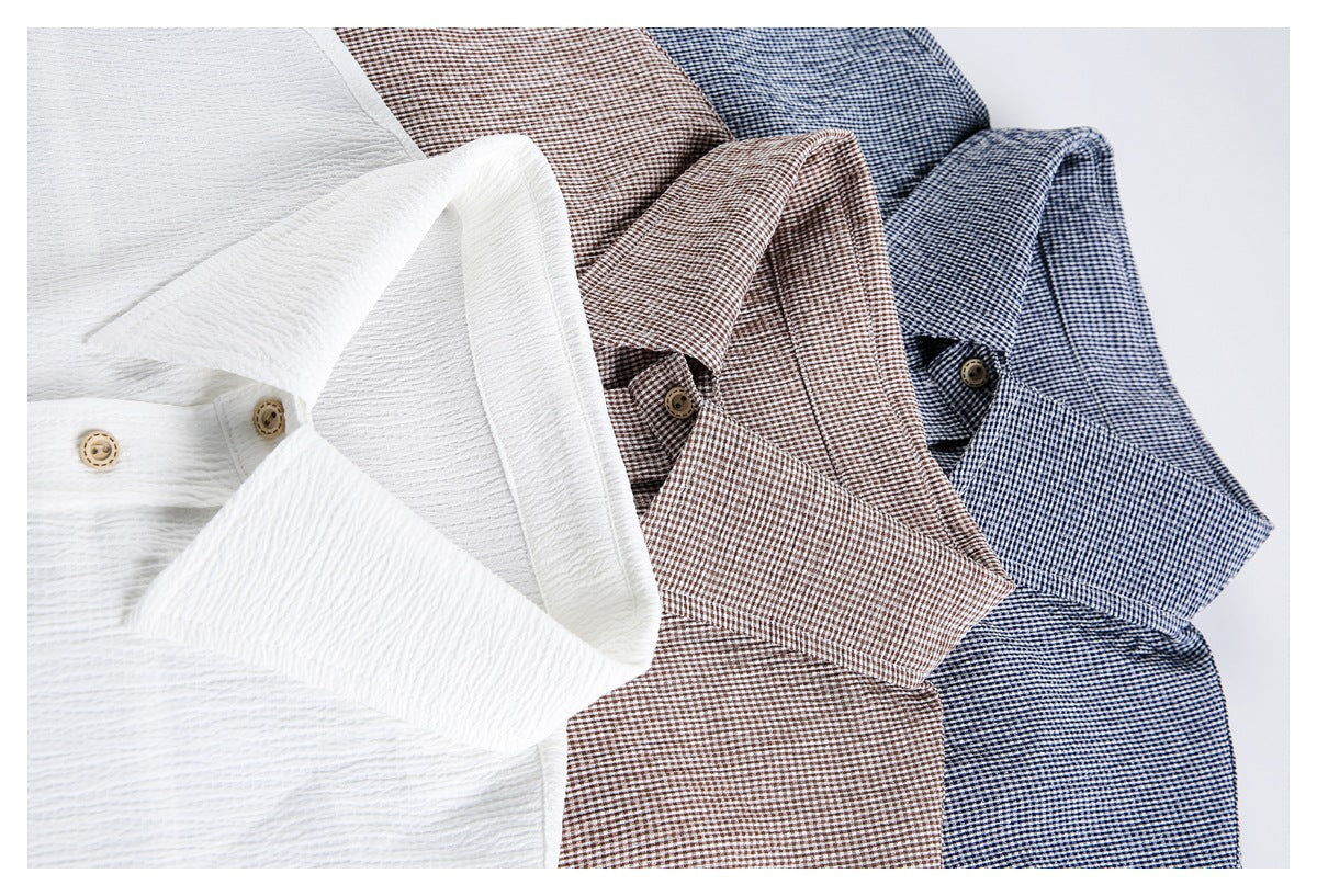 Three folded collared shirts in white, brown check, and navy check arranged side by side.