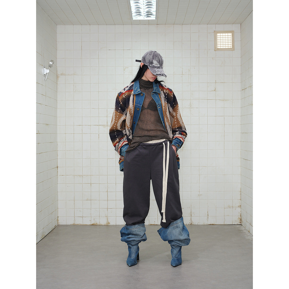Full-length model wearing a geometric-pattern jacket with denim trim, charcoal drawstring pants and slouchy denim boots.