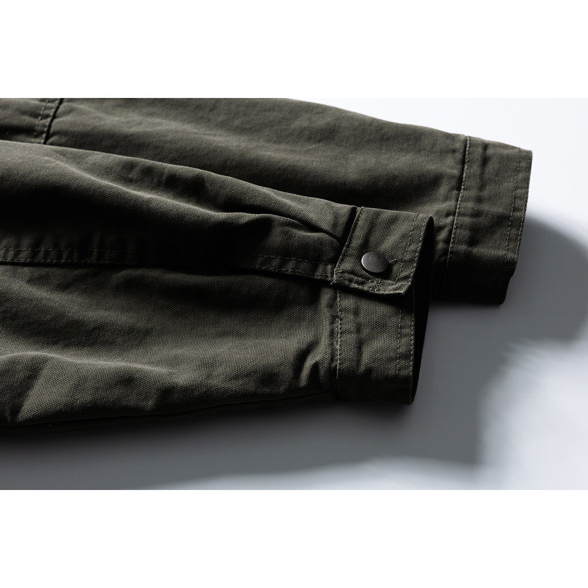 Close-up of an olive drab jacket sleeve cuff with a snap tab and visible stitching.