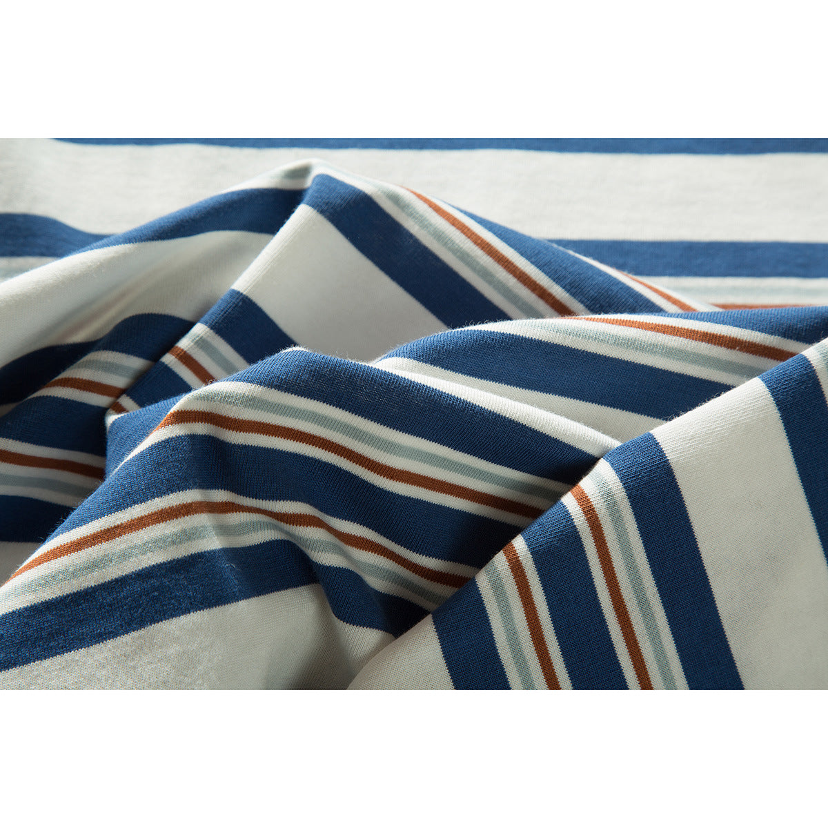 Close-up of folded cream fabric with broad blue stripes and thin rust and pale green stripes.