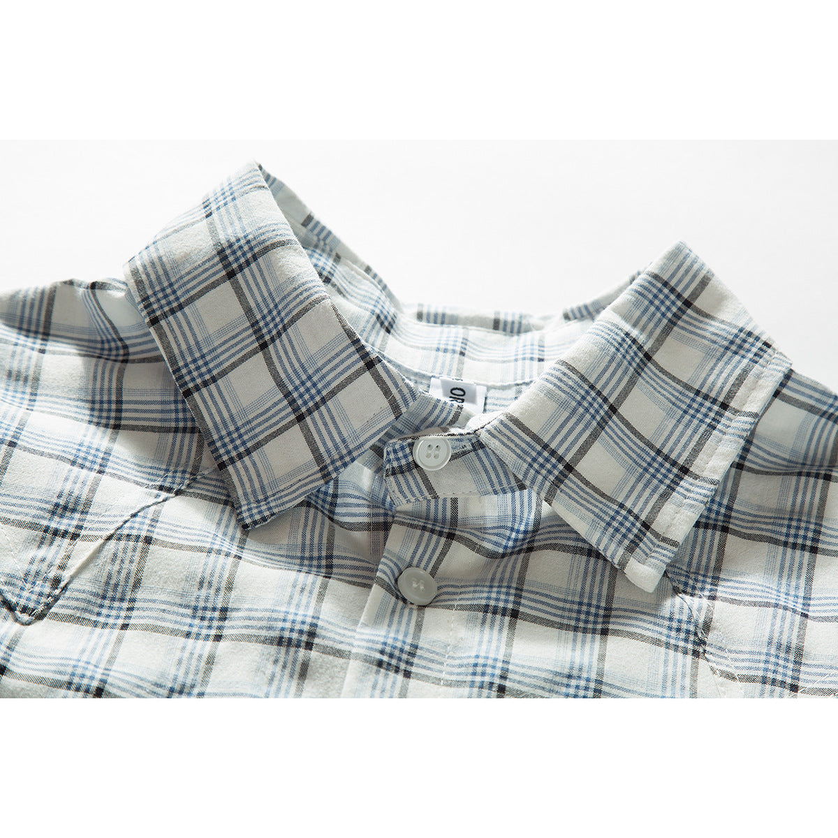 Close-up of a white shirt collar and buttons in a blue and charcoal plaid pattern.