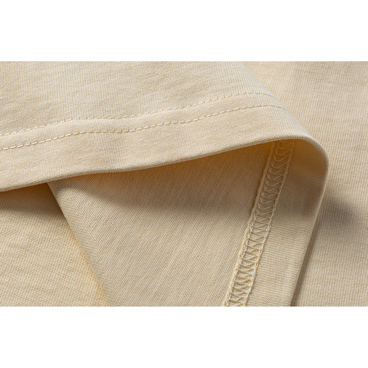 Close-up of a pale yellow T-shirt hem and overlocked side seam.