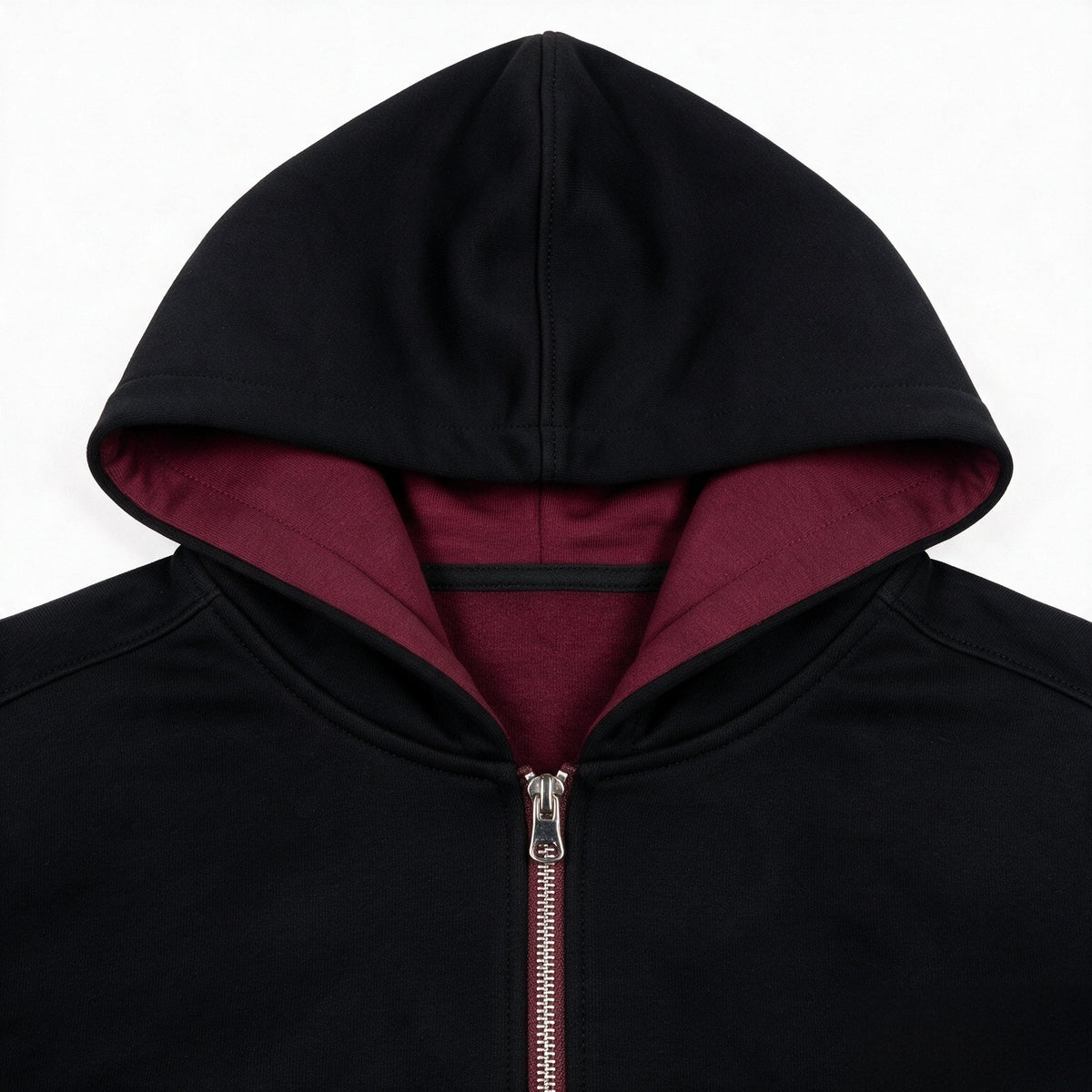 Close-up of a black zip-up hoodie with a burgundy-lined hood and silver zipper.